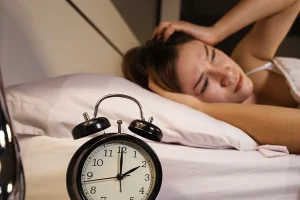 Woman laying in bed wide awake as the clock approaches 2 in the morning