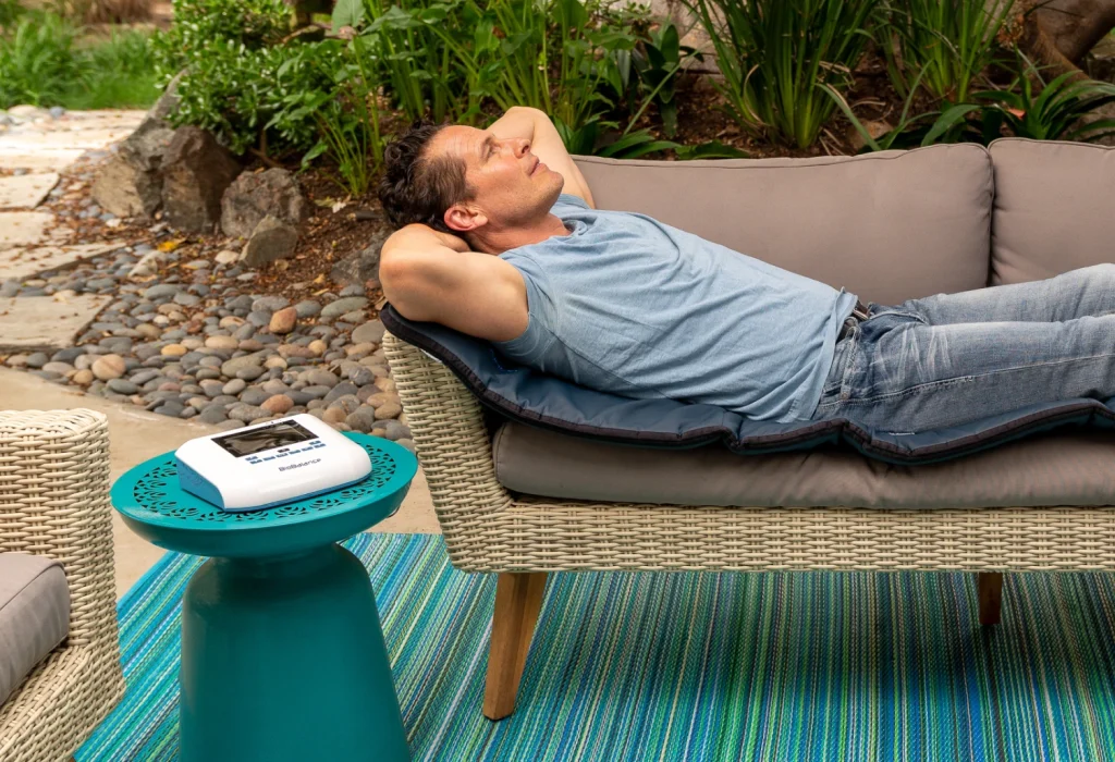 Man lying down with BioBalance PEMF device to his side