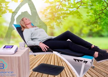Woman laying in chair and using PEMF mat from BioBalance